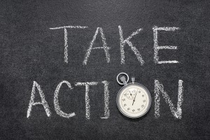 take action phrase handwritten on chalkboard with vintage precise stopwatch used instead of O
