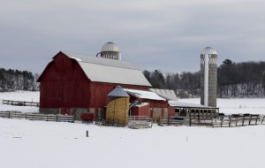 Family farm winter scene with red barn and snow covered landscape taken from a public road